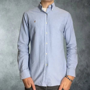 Polo Ralph Lauren skjorta ljusblå i size medium - Klassisk ljusblå skjorta från Ralph Lauren med button-down krage och broderad logga på bröstet. Skjortan är långärmad, har normal passform och är tillverkad i mjuk bomull. Perfekt för en clean och stilren look. Tröjan är i nytt skick och har inga skador:)                                                      Tveka ej på att skicka prisförslag😀