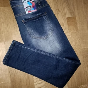 Dsquared2 blå jeans med tryck riktigt feta  - Snygga blå jeans från Dsquared2 med slitningar och tryckt lönnlöv på framsidan. Modellen har fem fickor, smal passform och coola detaljer som slitna partier och blekta effekter. Perfekt för dig som gillar streetstyle och vill sticka ut. Användmax tio ggr dom e som nya st blir ungefär 30/30