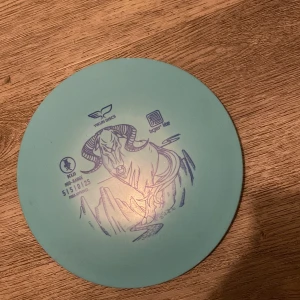 Yikun Discs Kui Tiger Line Mid-Range - Yikun Discs Kui Tiger Line mid-range discgolfdisk i blått. Märkt med 5/5/0/2.5 flight ratings och PDGA-godkänd. Snyggt motiv med get och berg. Lättare bruksspår men i gott skick, perfekt för både nybörjare och erfarna spelare.