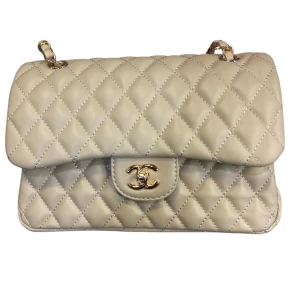 Beige  axelväska  - Säljer  Väskan är tillverkad i mjukt skinn och har en kedja som axelrem. Insidan är vinröd med logotyp och har flera fack, perfekt för dina essentials.