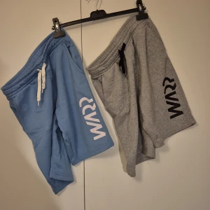 Två-pack - Blå och grå shorts från Warp - Två par mjuka shorts från Warp, ett par i ljusblått och ett par i grått. Båda har bred resår i midjan, snörning och tryckt Warp-logga på benet. Materialet är 60% bomull och 40% polyester, vilket gör dem sköna och flexibla. 