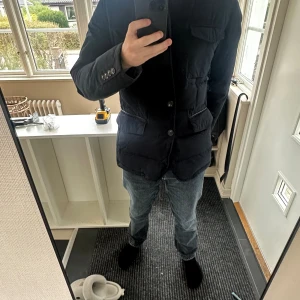 Svart dunjacka från Massimo Dutti L - Stilren svart dunjacka från Massimo Dutti i storlek L. Jackan har flera stora fickor framtill, knäppning med knappar och klassisk krage. Perfekt för kyligare dagar och ger en clean look till jeans eller chinos.