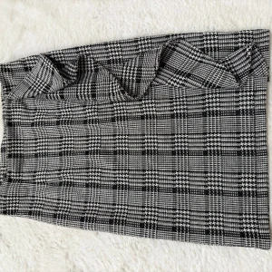 Rutig kortkjol från Bubbleroom - Snygg kortkjol från Bubbleroom i svartvitt rutigt mönster. Kjolen har en rak passform och är tillverkad i ett mjukt material som känns bekvämt mot huden. Perfekt för dig som gillar klassisk stil med en modern twist.