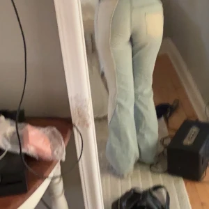 Ljusblå bootcut jeans  - Säljer ett par ljusblå bootcut jeans  med coola beige/vita paneler längs sidorna. Jeansen har låg midja och klassisk femficksdesign. Materialet är mjukt denim och passformen är loose nertill med snyggt utsvängda ben. Storlek M men känns som en S i midjan 