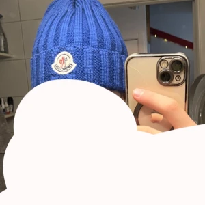 Blå ribbad Moncler mössa - Säljer en snygg blå mössa från Moncler med ribbad stickning och klassisk logga framtill. Perfekt för dig som vill ha en cool och varm accessoar till vintern. Passar dig som gillar streetstyle och exklusiva märken.