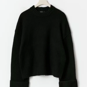 Svart stickad tröja - Säljer en svart stickad tröja med breda ribbade muddar vid ärmslut och nederkant. Tröjan har rund halsringning och långa ärmar med nedhasad axel för en chill vibe. Perfekt för lager-på-lager under kyliga dagar. Den är så skön att ha på sig och går med allt. Jag har tyvärr tröttnat på den så det är varför jag säljer den.