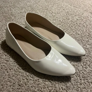 Vita ballerinaskor med spetsig tå - Snygga vita ballerinaskor med glansig finish och spetsig tå. Använda endast en gång på min student