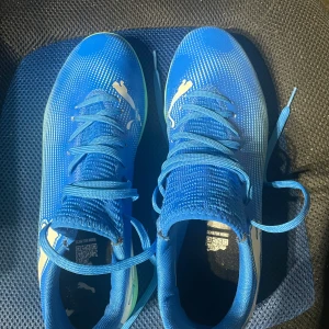 Blåa Puma fotbollsskor med snörning - Säljer ett par blåa fotbollsskor från Puma med vit logga på ovansidan och ljusgröna sulor. Har använt de en gång när jag skulle spela en inomhus cup och är för små nu och säljer de. Kan diskutera pris! 