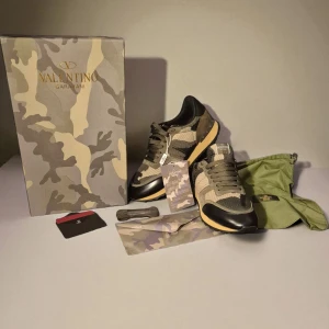 Valentino Rockrunner sneakers camouflage - Snygga Valentino Rockrunner sneakers med camouflage-mönster i beige, grön och svart. Skorna har detaljer i mocka, mesh och skinn, samt en robust gummisula med nitar på hälen. Klassisk snörning och ikonisk design – perfekt för dig som vill sticka ut.