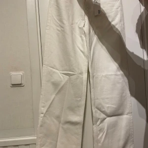 Vita wide leg jeans från 157, XS - Säljer ett par vita jeans från 157 i modellen Optiwide. Byxorna har midwaist, breda ben och full längd. Klassisk femficksdesign och tillverkade i bomullstyg. Perfekta för dig som gillar en avslappnad och trendig look.