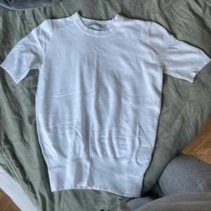 Vit t-shirt från Zara - En basic vit t-shirt från Zara med rund halsringning och korta ärmar. T-shirten är i mjukt material och har en klassisk passform som funkar till allt. Perfekt att styla med jeans eller shorts 