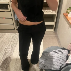 Svarta kostymbyxor med bootcut - Säljer ett par svarta kostymbyxor med bootcut-snitt och normal passform. Byxorna har klassisk midja och raka ben som blir lite vidare nertill. Perfekta till en snygg topp eller skjorta. Materialet känns mjukt och följsamt. 