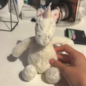 Jellycat Enhörning Gosedjur - Supermjuk Jellycat enhörning i vitt med rosa detaljer och glittrande horn. I fint skick, inga synliga fläckar eller skador. Perfekt som present eller mysig kompis till barn. Originaletikett kvar.