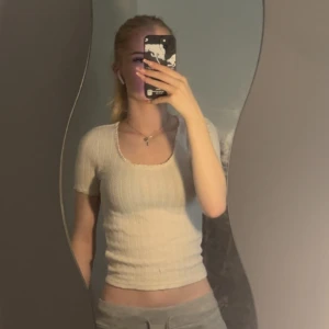 Vit ribbad topp Holly & Whyte XS - Supersöt vit ribbad topp från Holly & Whyte i storlek XS. Modellen är figurnära med korta ärmar och rundad urringning. Tunt, stretchigt material som sitter snyggt och är perfekt till jeans eller kjol. Enkel och fräsch stil med diskreta detaljer.