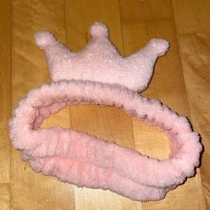 Rosa fluffigt diadem med krona - Supergulligt rosa diadem i mjuk och fluffig polyester med en söt krona på toppen. Perfekt accessoar för att ge en lekfull touch till din look eller hålla håret borta vid sminkning. Stretchig och bekväm att bära hela dagen.