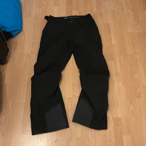 Svarta skidbyxor Helly Hansen 2XL - Svarta skidbyxor från Helly Hansen i storlek 2XL. Byxorna har raka ben, förstärkta partier vid bensluten och praktiska fickor med dragkedja. Perfekta för vinterns alla äventyr och outdoor-aktiviteter. Minimala slitagehål vid benslutet annars toppenskick!