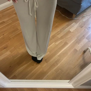 Vita mjukisbyxor med snörning - Säljer ett par vita mjukisbyxor med breda ben och dragsko i midjan. Byxorna är i mjukt material och har en relaxed fit som är perfekt för chill dagar. Snyggt minimalistiska och superbekväma, passar dig som gillar en enkel och clean stil.