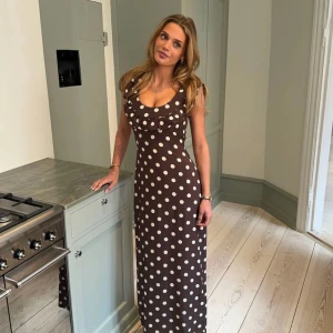 Prickig klänning designbysi  - Supersnygg brun långklänning med vita prickar och volangdetalj vid urringningen. Klänningen är ärmlös och har en figurnära passform som ger en riktigt chic look. Inköpt i början av sommaren men använd 1-2 gånger pga lite liten för mig… storlek XS/S