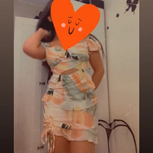 Färgglad kortklänning med cut-out - Superfin kortklänning i pastelliga toner puffiga korta ärmar, cut-out vid midjan och snörning i sidan. Materialet känns lätt. Använd en gång