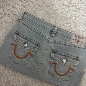 True religion jeanskjol - Säljer en ljusblå jeanskjol från true religion i kort modell. Kjolen har klassiska fem fickor, rå kant nedtill och knapp samt dragkedja framtill. Perfekt för dig som gillar en chill och trendig stil. Passar till både t-shirt och hoodie. 