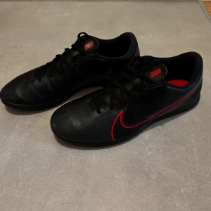 Svarta Nike fotbollsskor med röd swoosh - Använda vid fåtal tillfällen. Skicket är nästan som nya.