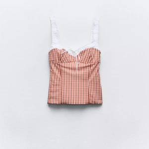 Rutig röd och vit linnetopp med knyt - Supersöt linnetopp från Zara med rödvitt rutigt mönster och vita axelband. Toppen har en söt knytning framtill och breda axelband i vitt tyg. 