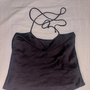 Svart satin linnetopp Gina Tricot - Snygg svart linnetopp från Gina Tricot i glansigt satinmaterial. Toppen har tunna axelband som kan knytas. Säljer då den tyvärr är för liten i storleken 🖤