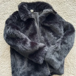 Svart pälsjacka med dragkedja - Säljer en fluffig och snygg pälsjacka i svart ton med dragkedja framtill. Jackan har en klassisk krage och långa ärmar, perfekt för dig som vill ha en cool och varm look. Pälsen är mjuk och ger en lyxig känsla. Storlek 158 (XXS) 