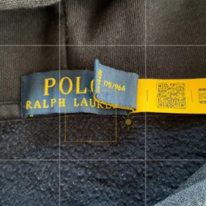 Polo Ralph Lauren Hoodie  - Hoodie från Polo Ralph Lauren med ikonisk björn på framsidan som målar färgglada bokstäver. Tröjan har huva med snörning och långärmade ärmar. Mjuk insida och klassisk passform.
