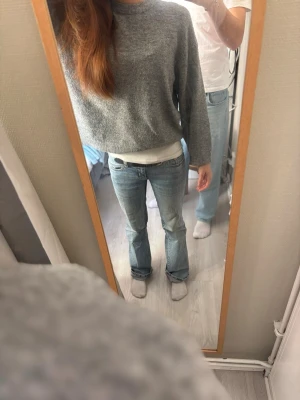 Grå stickad tröja från 157, S - Mysig grå stickad tröja från 157 i storlek S. Tröjan har en rak, lite boxig passform och är gjord i mjukt material med ribbade muddar vid halsen. Perfekt till höst och vinter för en chill och enkel look.