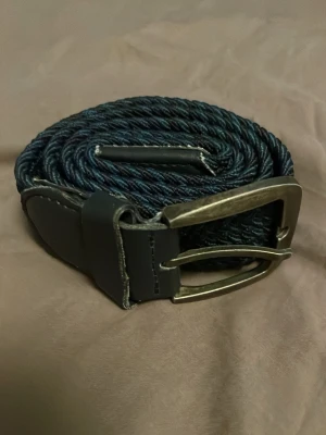 Brunt svart flätat bälte - Ett riktigt snyggt blå svart mönstring flätat bälte. Passar till alla tillfällen. Skick 8/10 aldrig använt men suttit i garderoben ett bra tag.