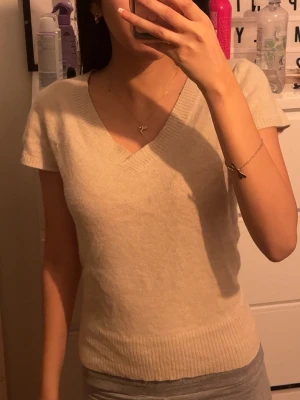 Beige stickad v-ringad topp - Mysig beige stickad topp med v-ringning och korta ärmar som inte kommer till användning längre 