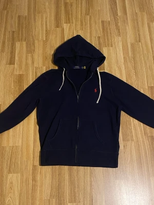 Polo Ralph lauren zip hoodie mörkblå M - Jag säljer en polo Ralph lauren zip hoodie i storlek M pga att den är för liten. Skick 9,5/10 knappt använd. Nypris ca 2200kr. Pris kan diskuteras vid en snabb affär!
