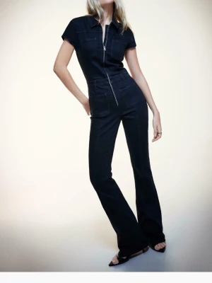 Svart jeans jumpsuit med dragkedja - Snygg svart jumpsuit i jeansmaterial med korta ärmar, krage och markerade sömmar.  Märktet är bershka. Den är helt slut såld på hemsidan. Jag har aldrig använd den!