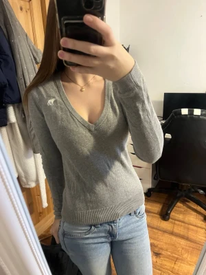 Abercrombie & Fitch tröja - Säljer en grå v-ringad tröja från Abercrombie & Fitch med lång ärm och ribbade muddar. Den är lite nopprig men det ser man också i bilderna, Det är inget som påverkar tröjan direkt. Jätte bekväm tröja och i storlek Xs. Jag säljer den då den blivit lite för liten och behöver plats för nya kläder💕 lägg gärna bud! 