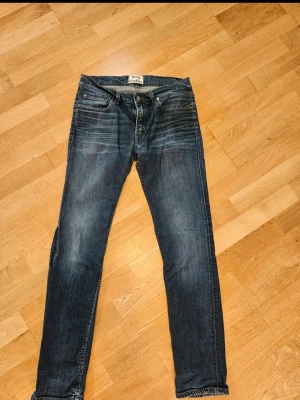 Blå jeans från Acne Studios, strl 31/32 - Säljer ett par snygga blå jeans från Acne Studios i modellen Ace OREO. Klassisk femficksdesign, normal passform och raka ben. Jeansen är i mjukt bomullsmaterial med lite stretch för extra komfort. Perfekta till vardagslooken!