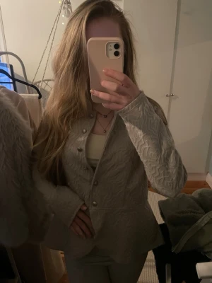 Beige strukturerad kavaj från RoseBud - Säljer en beige kavaj från RoseBud med snyggt strukturerat tyg och rundad halsringning. Jackan har dekorativa knappar framtill och en figurnära passform som ger en clean och modern look. Perfekt att styla med jeans eller kjol för en trendig vibe. Storlek M men passar mig som är S