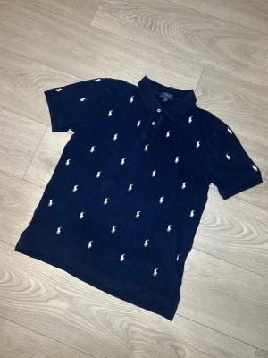 Ralph Lauren piké, mörkblå, storlek S/M - Hej! Säljer nu denna Mörkblåa Ralph Lauren pikén. Kortärmad samt storlek XL, kvinnostorlek S/M i herr. Inga skador eller fläckar. Riktigt unik och snygg piké!  Skickar alltid inom 24h efter köp🤩 Frågor om mått eller annat? Hör av dig!