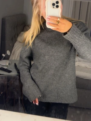 Grå stickad tröja med lång ärm - Mysig grå stickad tröja med lång ärm och enkel, klassisk design. Tröjan har en rak passform och rund halsringning, perfekt för lager på lager under kyliga dagar. Passar dig som gillar en basic men ändå snygg look.