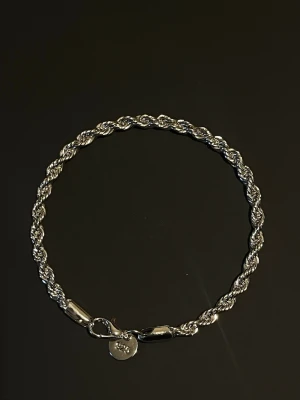 Silverfärgat Tvistat Länkarmband - Ett elegant armband med tvistade silverlänkar som ger en stilren och modern look. Perfekt för både vardag och fest. Bredd: 4mm och längd: 20cm