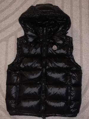 Moncler väst - Säljer en tvärfet Moncler väst i utmärkt skick. Enda defekten är att serietidningen inuti lossnat litegrann. Västen är i storlek 2 vilket motsvarat S/M. Luvan är avtagbar och går att ta av och sätta på med knapparna. Hör av er vid funderingar 😊 pris ej hugget i sten!