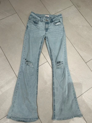 Bootcut ljusblå jeans Nelly - Bootcut jeans i ljusblå tvätt och rosa detaljer från Nelly, nypris 700 kr. Uppsydda för att passa mig i längden, 158. Går däremot att sprätta upp till den fulla originallängden. Har små slitningar i botten, och fläckar på insidan som var svåra att få bort