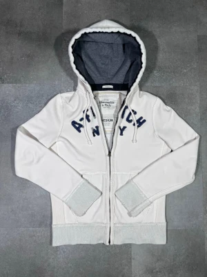 Vintage y2k abercrombie & fitch zip up hoodie - Säljer en vintage Y2K Abercrombie & Fitch zip-up hoodie i snygg vit färg. 🧵 Märke: Abercrombie & Fitch 👕 Storlek: M 🎨 Färg: Vit 📌 Design: Zip-up hoodie, klassisk Y2K-stil 📍 Skick: Mycket bra, se bilder!  Beskrivning: • Äkta Y2K-design från Abercrombie & Fitch • Zip-up modell med huva – både praktisk och stilren • Bekväm och varm, perfekt för vardag och layering • Inga fläckar, noppor eller skador (kontrollera bilder) • Lätt att matcha med jeans, cargobyxor eller mjukisbyxor  Har du några frågor 