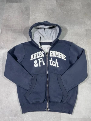 Vintage abercrombie & fitch - Säljer en vintage Y2K Abercrombie & Fitch zip-up hoodie i snygg navy färg. 🧵 Märke: Abercrombie & Fitch 👕 Storlek: M 🎨 Färg: Navy / mörkblå 📌 Design: Zip-up hoodie i klassisk Y2K-stil 📍 Skick: Mycket bra, se bilder!  Beskrivning: • Äkta Y2K-design från Abercrombie & Fitch • Zip-up modell med huva – praktisk och stilren • Bekväm och varm, perfekt för vardag och layering • Inga fläckar, noppor eller skador (kontrollera bilder) • Lätt att matcha med jeans, cargos eller mjukisbyxor  Har du några frå