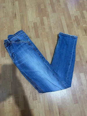 Dondup Doillon - Snygga blå jeans med klassisk femficksdesign och raka ben. Jeansen har en lätt tvättad look med subtila slitningar och kontrastsömmar. Bakfickorna har dekorativa sömmar och en liten metall-detalj. Perfekt för dig som gillar enkel och stilren denim.