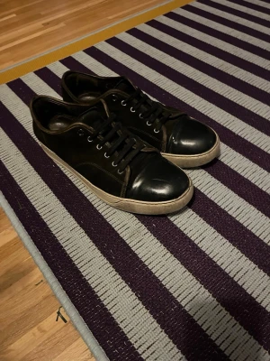 Svarta Lanvins - Lanvin sneakers i svart mocka med glans. Snygga sköna skor som passar till massa olika outfits! Perfekt för dig som gillar mode! Slitna men har mycket kvar i sig. Pris kan diskuteras privat! 