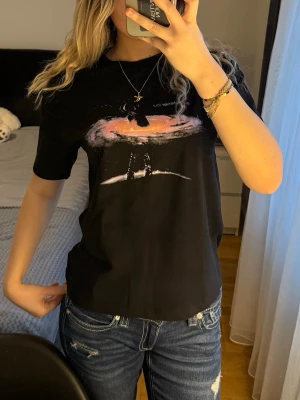 Sweetener Tour Ariana Trande t-shirt från H&M  - Säljer en svart Sweetener Tour t-shirt från H&M Divided i storlek XS. Framsidan har ett coolt tryck med en siluett och texten 'sweetener tour', medan baksidan visar turnéstäder och årtal. T-shirten är kortärmad och gjord i mjuk bomull, perfekt för dig som gillar Ariana Grande.