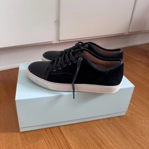 Lanvin DBB1 Nappa Cap Toe Sneaker Navy - Säljer mina Lanvin skor med färgen Navy Blue. Storlek UK 9 vilket motsvarar 43 men passar 44 också. Bra skick, använda varsamt. Kartong och tillbehör följer med. Kvittot kan tas fram om någon behöver.