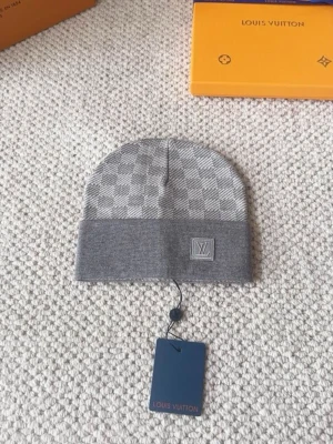 Grå rutig mössa - Snygg grå mössa med klassiskt rutigt mönster och framtill. Mössan har en bred uppvikt kant och är stickad i mjukt material som känns lyxigt. Perfekt accessoar för att lyfta din vinterstil.