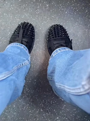 Svarta glittriga sneakers med nitar - Säljer ett par svarta sneakers från Christian Louboutin med glittrig yta och svarta nitar över hela ovandelen. Skorna har snörning och en ikonisk röd sula. Perfekt för dig som vill sticka ut med en edgy och lyxig stil. Fick dem i present!